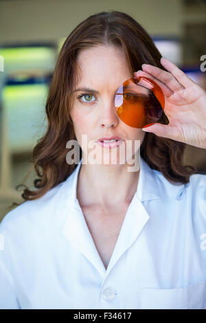 Opticien sérieux holding up lens Banque D'Images