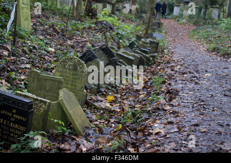 Rangée de tombes dans la région de Abney Park Cemetery, Stoke Newington, Hackney, Londres, Royaume-Uni, certains se penchant et diminué au cours le long d'un chemin de terre Banque D'Images