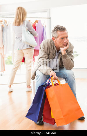 Bored man attend son shopping woman Banque D'Images