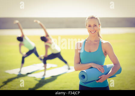 Smiling blonde sportive devant vos amis faisant des exercices Banque D'Images