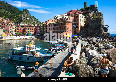 Les touristes et les habitants vous détendre sur Vernazza's Harbour murs dans l'Italie Cinque Terre Banque D'Images