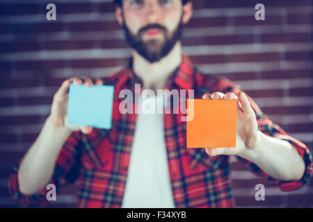 Portrait of man holding orange et bleu notes adhésives Banque D'Images