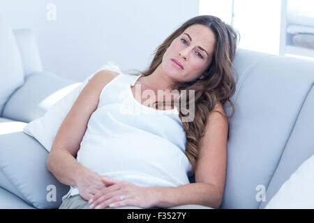 Triste pregnant woman leaning on sofa Banque D'Images