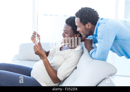 Femme enceinte montrant la photo pour l'époux à la maison Banque D'Images