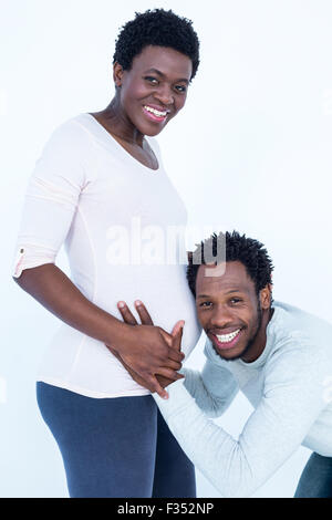 Portrait of happy smiling mari l'écoute de sa femme enceinte ventre Banque D'Images