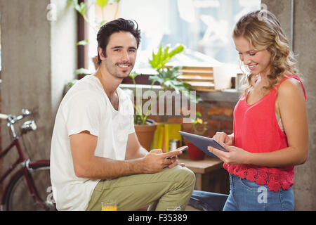 Portrait of businessman with smart phone while woman using digital tablet in office Banque D'Images