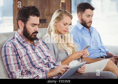 Les gens d'affaires à l'aide de technologies tout en étant assis sur le canapé Banque D'Images