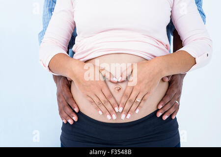Au milieu de deux mains sur pregnant belly against white background Banque D'Images