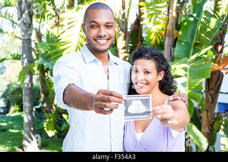 Portrait of happy man with pregnant wife holding sonogram Banque D'Images