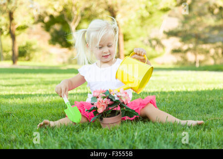 Cute Little Girl Playing jardinier ses outils et pot de fleurs. Banque D'Images