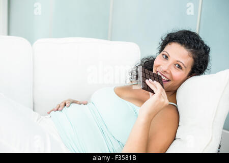 Happy pregnant woman eating chocolate bar Banque D'Images