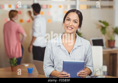 Portrait of happy businesswoman holding digital tablet in office Banque D'Images