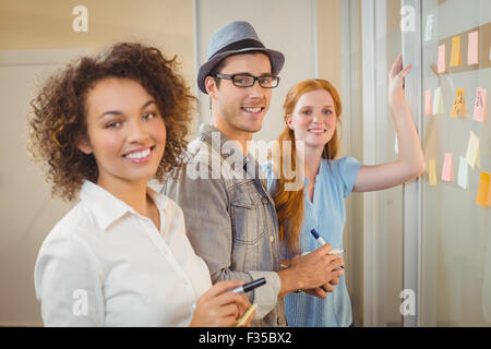 Portrait of business people standing by glass wall Banque D'Images