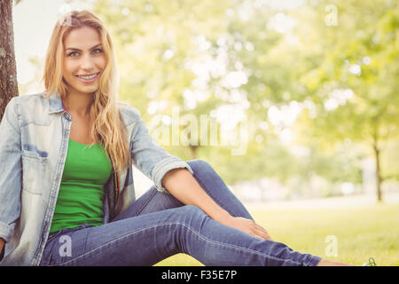 Portrait of happy woman sitting under tree Banque D'Images
