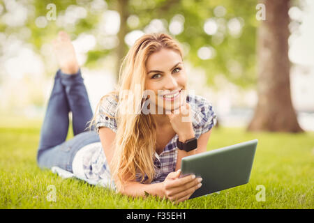 Portrait of smiling woman with hand on chin et holding digital tablet at park Banque D'Images
