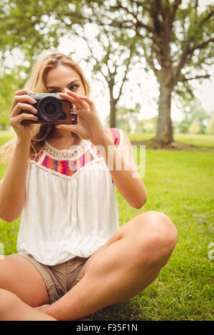 Woman holding camera while sitting on grass Banque D'Images