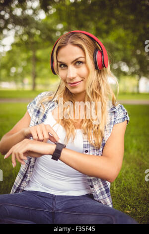 Portrait of smiling woman listening to music et à l'aide de smartwatch Banque D'Images
