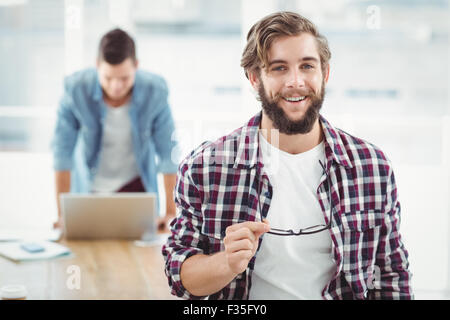 Portrait of smiling businessman holding eyeglasses Banque D'Images
