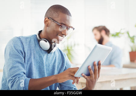 L'homme souriant avec des écouteurs lors de l'utilisation de digital tablet Banque D'Images