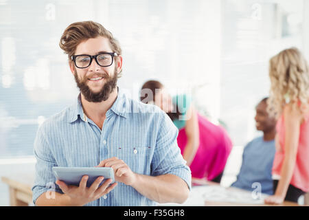 Portrait of smiling man wearing eyeglasses using digital tablet Banque D'Images