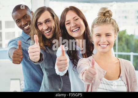 Portrait of happy business team with Thumbs up en étant debout dans la rangée Banque D'Images