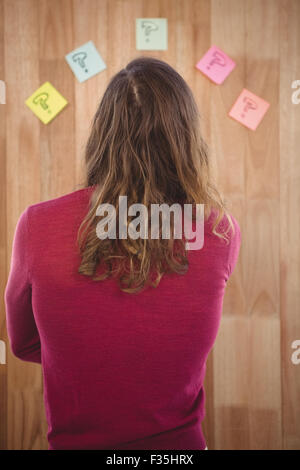 Homme debout en face de post-it collé sur le mur en bois Banque D'Images