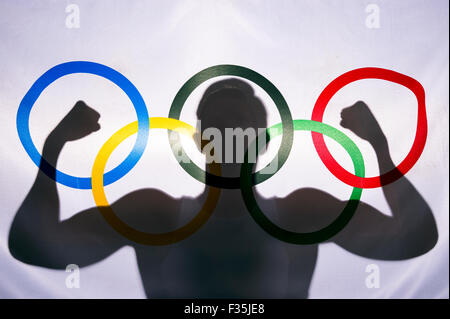 RIO DE JANEIRO, Brésil - 3 février, 2015 : Silhouette d'athlète flexing muscles derrière les anneaux de drapeau olympique. Banque D'Images