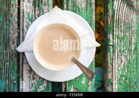 Tasse de café avec de la crème qui est sur le vieux banc en bois à l'automne parc. Vue de dessus, selective focus Banque D'Images