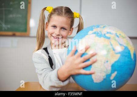 Cute élève holding globe dans une salle de classe Banque D'Images