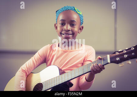 Smiling élève qui joue de la guitare dans une salle de classe Banque D'Images