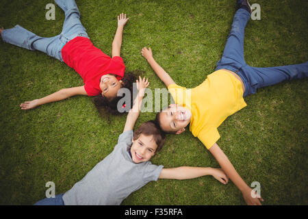 Cute pupils lying on grass smiling Banque D'Images