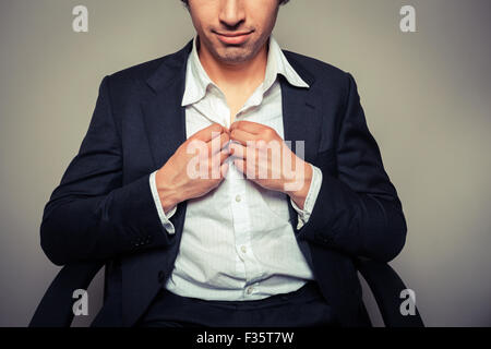 Young businessman sitting in office chair est à boutonner sa chemise Banque D'Images