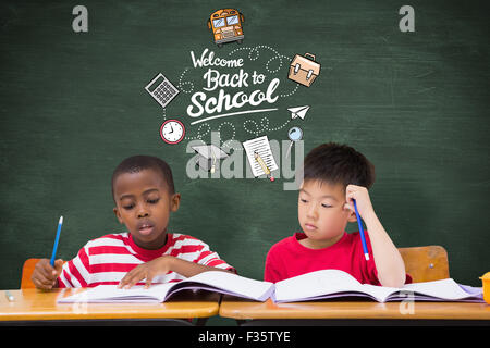 Image composite de cute pupils écrit at desk in classroom Banque D'Images