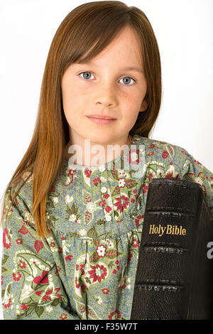 Jeune enfant tenant une bible sur un fond blanc Banque D'Images