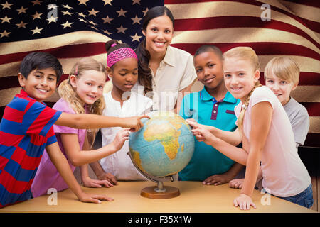 Image composite de mignons petits élèves et enseignant looking at globe in library Banque D'Images