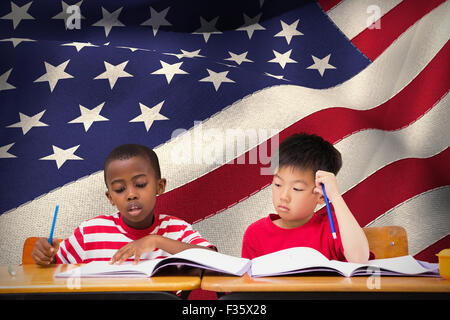 Image composite de cute pupils écrit at desk in classroom Banque D'Images