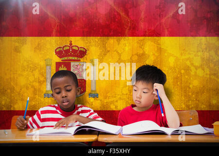 Image composite de cute pupils écrit at desk in classroom Banque D'Images
