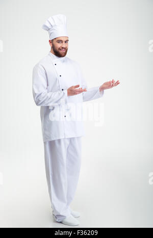 Full Length portrait of a happy chef cuisinier montrant copyspace sur les paumes isolé sur fond blanc Banque D'Images