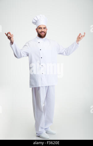 Full Length portrait of a smiling chef cuisinier montrant le geste de bienvenue isolé sur fond blanc Banque D'Images