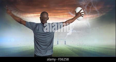 Libre de sportsman avec bras levés holding rugby ball Banque D'Images