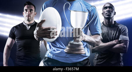 Image composite de mid section de sportif holding trophy et ballon de rugby Banque D'Images