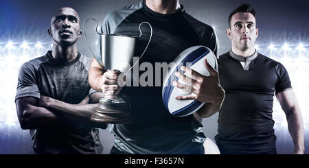 Image composite du milieu du rugby player holding trophy réussie et la balle Banque D'Images