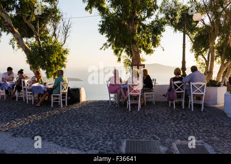 Personnes assises prêt pour le coucher du soleil avec vue sur la caldeira de Santorin, un restaurant Firostefani, Cyclades, Grèce Banque D'Images