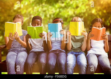 Image composite de la lecture de livres pour enfants au parc Banque D'Images