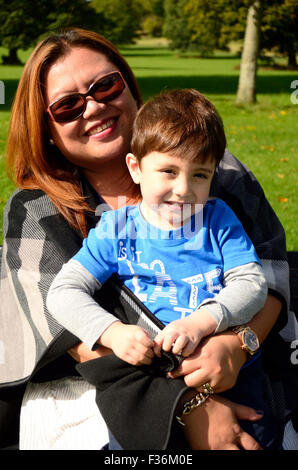 Une mère et son enfant s'assit et câlins sur un banc dans le parc. Banque D'Images