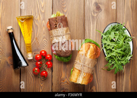 Deux sandwichs avec de la salade, jambon, fromage et tomates, salade et épices sur table en bois. Top View with copy space Banque D'Images