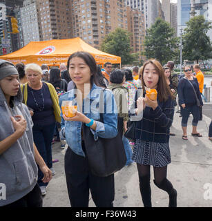 Des centaines d'échantillons de manger Panda Express' Poulet Orange signature à un évènement promotionnel à Columbus Circle à New York le dimanche, Septembre 27, 2015. Panda Express, omniprésents dans les centres commerciaux et les aéroports, a un projet d'expansion dans New York avec deux branches l'ouverture le mois prochain avec un troisième prévue plus tard dans l'année. Le restaurant est une propriété privée et possède 1800 magasins dans le monde entier. (© Richard B. Levine) Banque D'Images