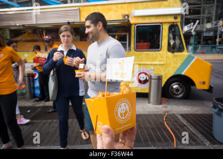 Des centaines d'échantillons de manger Panda Express' Poulet Orange signature à un évènement promotionnel à Columbus Circle à New York le dimanche, Septembre 27, 2015. Panda Express, omniprésents dans les centres commerciaux et les aéroports, a un projet d'expansion dans New York avec deux branches l'ouverture le mois prochain avec un troisième prévue plus tard dans l'année. Le restaurant est une propriété privée et possède 1800 magasins dans le monde entier. (© Richard B. Levine) Banque D'Images