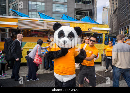 Des centaines d'échantillons de manger Panda Express' Poulet Orange signature à un évènement promotionnel à Columbus Circle à New York le dimanche, Septembre 27, 2015. Panda Express, omniprésents dans les centres commerciaux et les aéroports, a un projet d'expansion dans New York avec deux branches l'ouverture le mois prochain avec un troisième prévue plus tard dans l'année. Le restaurant est une propriété privée et possède 1800 magasins dans le monde entier. (© Richard B. Levine) Banque D'Images