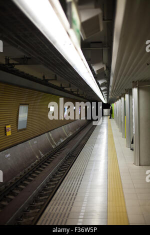 Plate-forme du métro avec l'homme appuyé contre un pilier loin en arrière-plan Banque D'Images